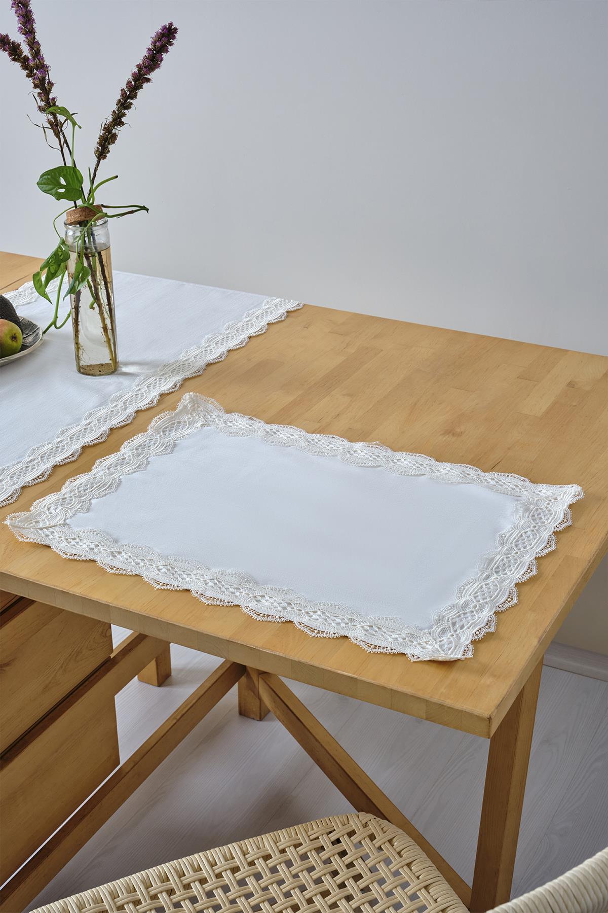 Weißes Platzset mit Spitzenrand auf einem Holztisch, dekorative Tischdekoration