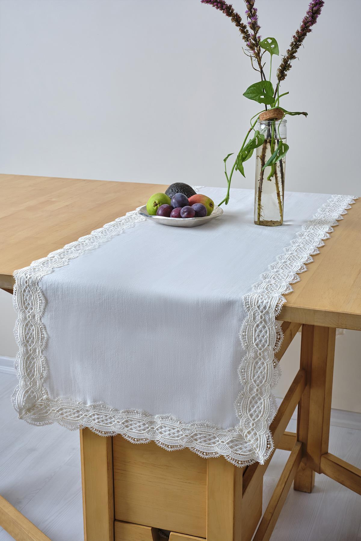 Weißer Tischläufer mit Spitzendetails, mit Obstteller und Glasvase auf einem Holztisch