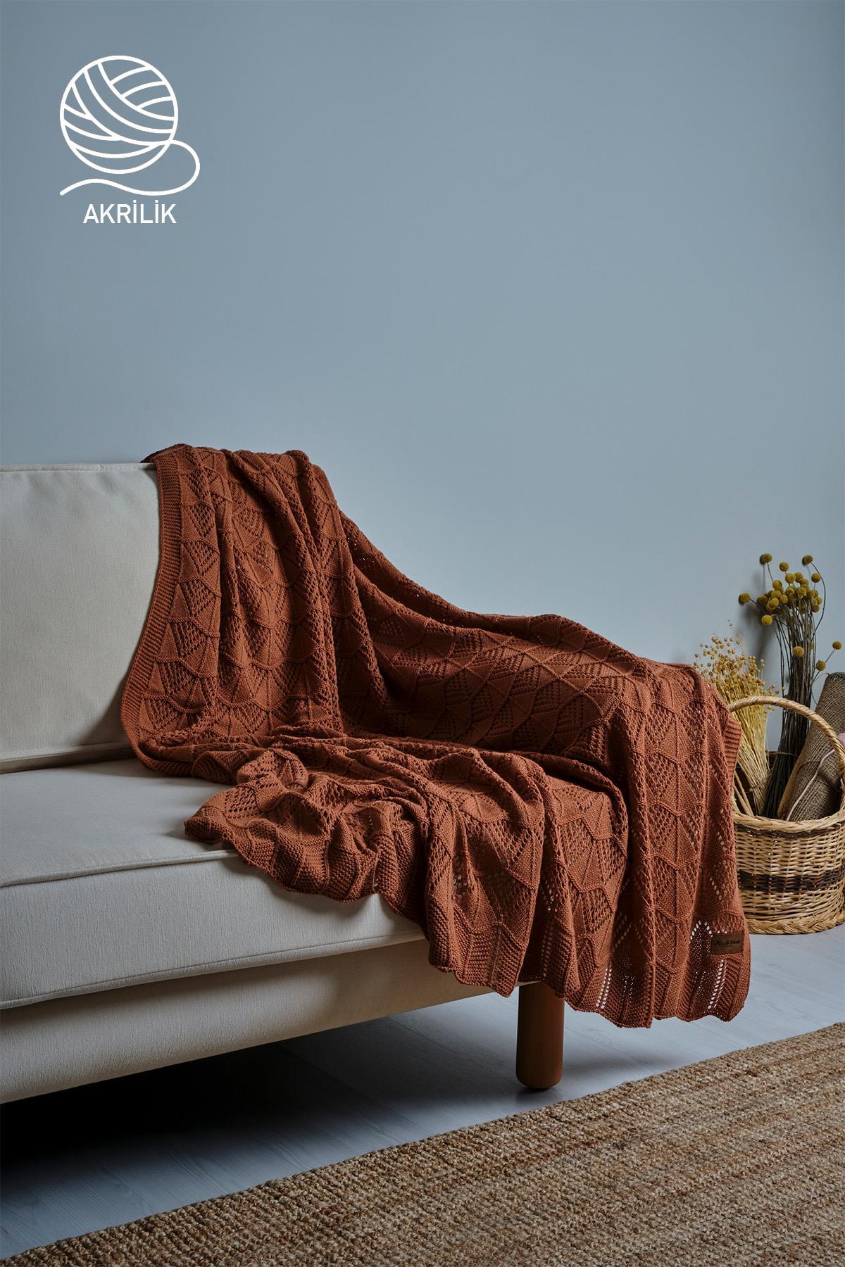 Braune, grob gestrickte Acryl-TV-Decke auf einem cremefarbenen Sofa mit dekorativem Korb