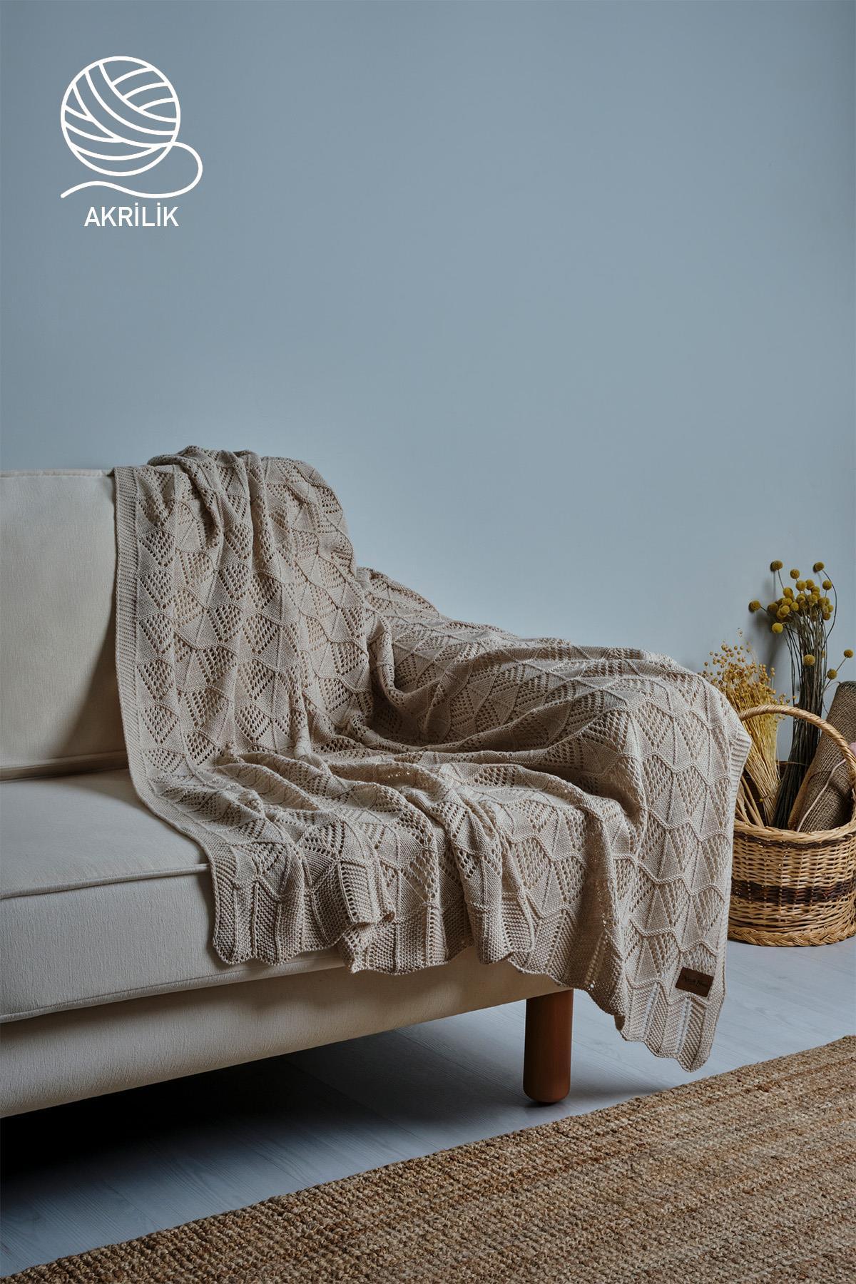 Cremefarbene Strickdecke aus Acryl für das Sofa, drapiert auf einer Couch in einem modern eingerichteten Wohnzimmer