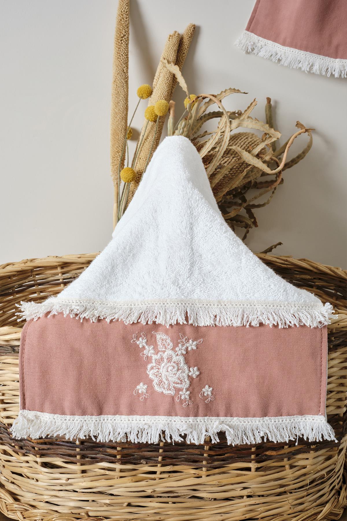 Kleine rosa Handtuch mit Spitze und besticktem Rand, dekorativ in einem Korb präsentiert.