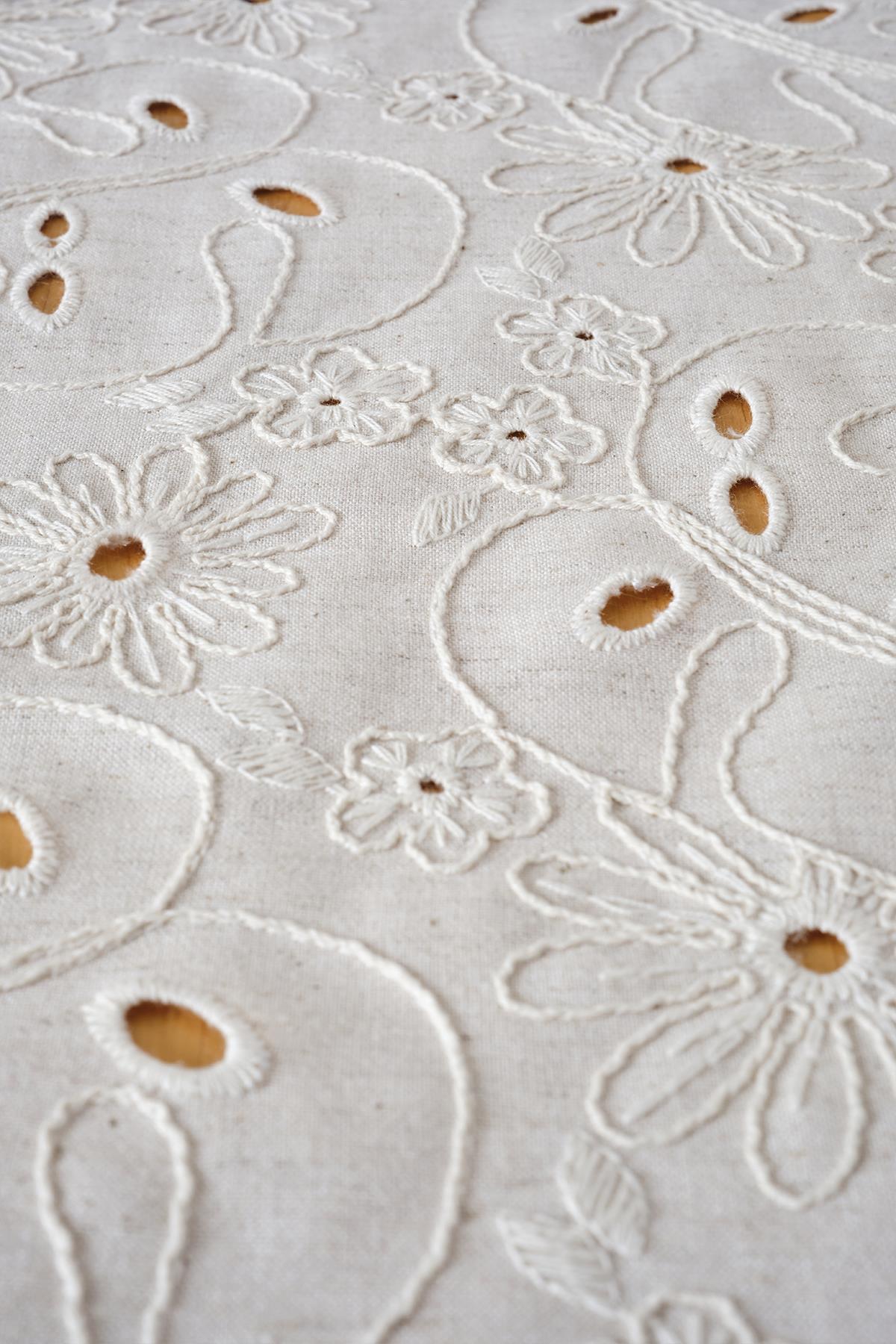 Detailansicht eines cremefarbenen Tischläufers aus Baumwollgewebe mit Blumenmuster