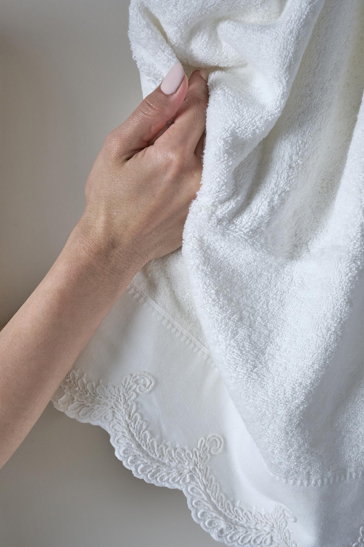 Handbesticktes weißes Handtuch mit Spitzenbordüre, in der Hand gehalten
