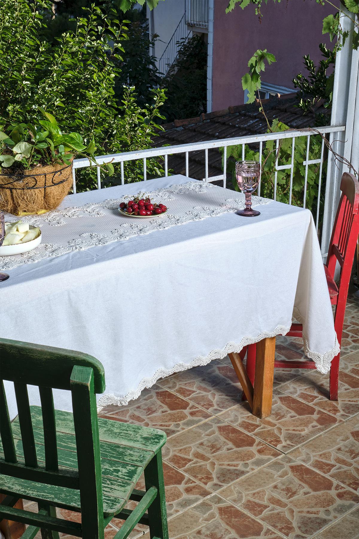 Balkontisch mit weißer Tischdecke mit Spitzendetails, daneben ein roter und ein grüner Stuhl
