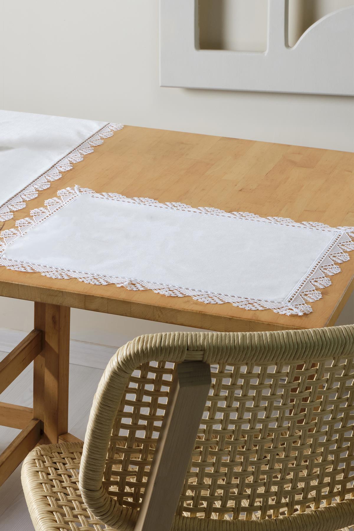 Weiße Platzmatte mit Spitzenrand, stilvolle Tischdekoration auf einem Holztisch
