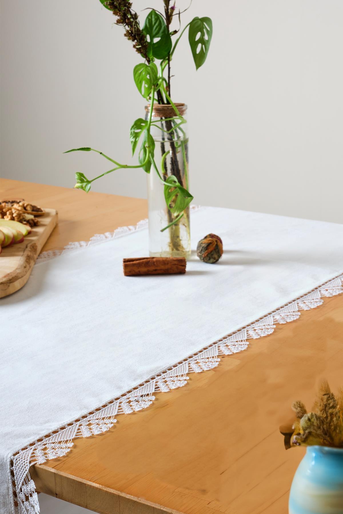 Weißer Tischläufer aus Spitze, stilvolle und elegante Dekoration auf einem Holztisch.