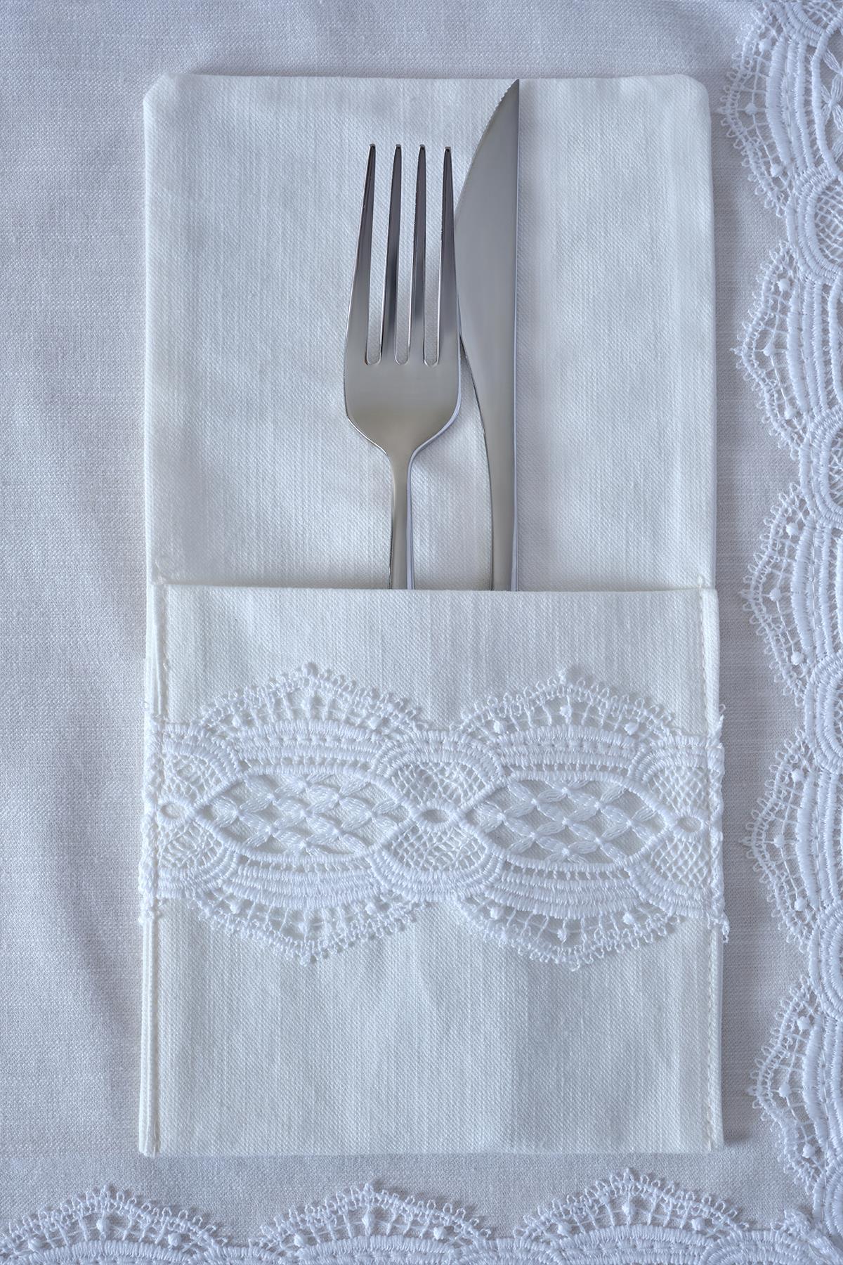 Gabel und Messer auf einer weißen Serviette mit Spitzendetail, elegante Tischdekoration