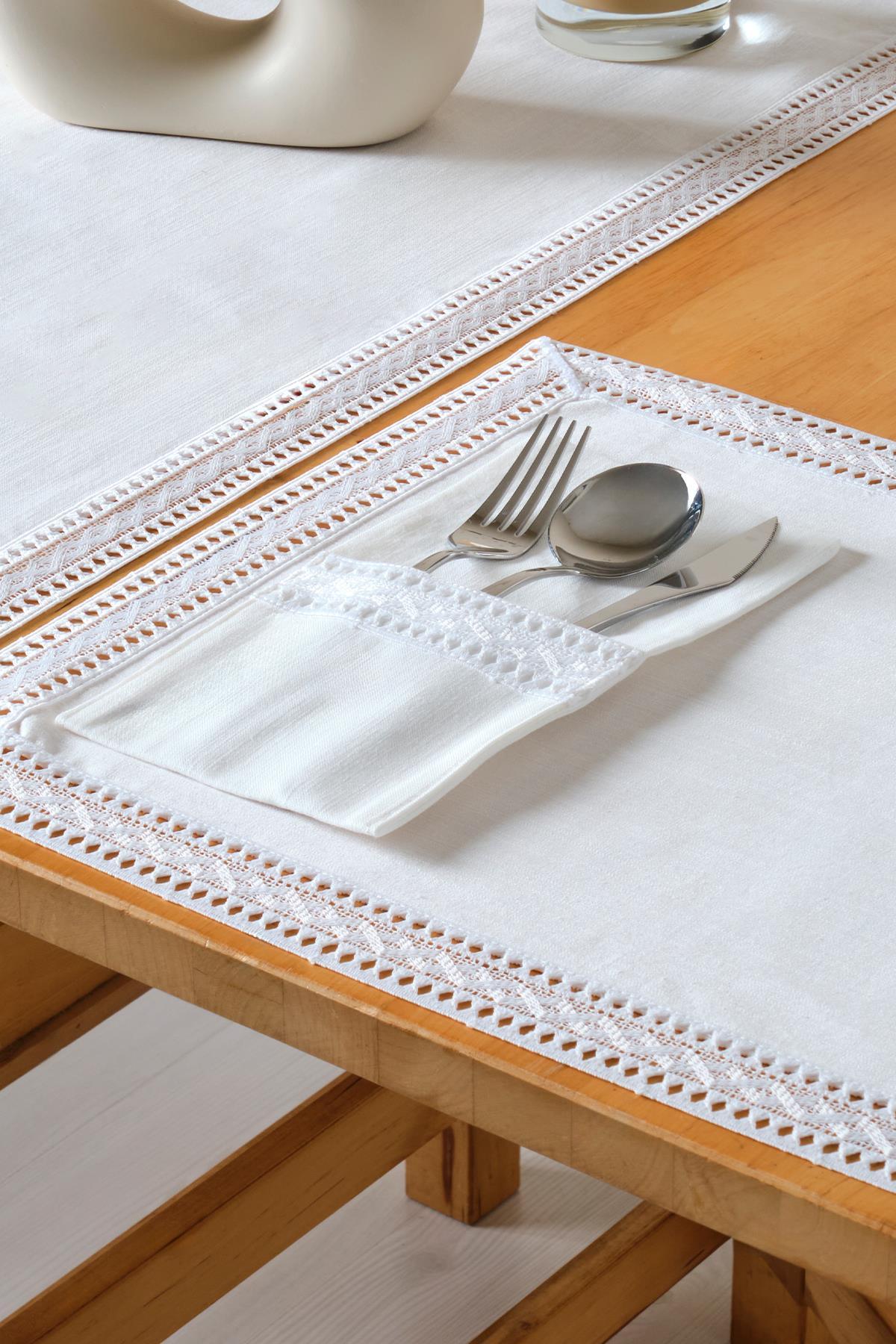 Stilvolle Tischdekoration mit weißer Spitzentischdecke und Besteckset in einer Tasche