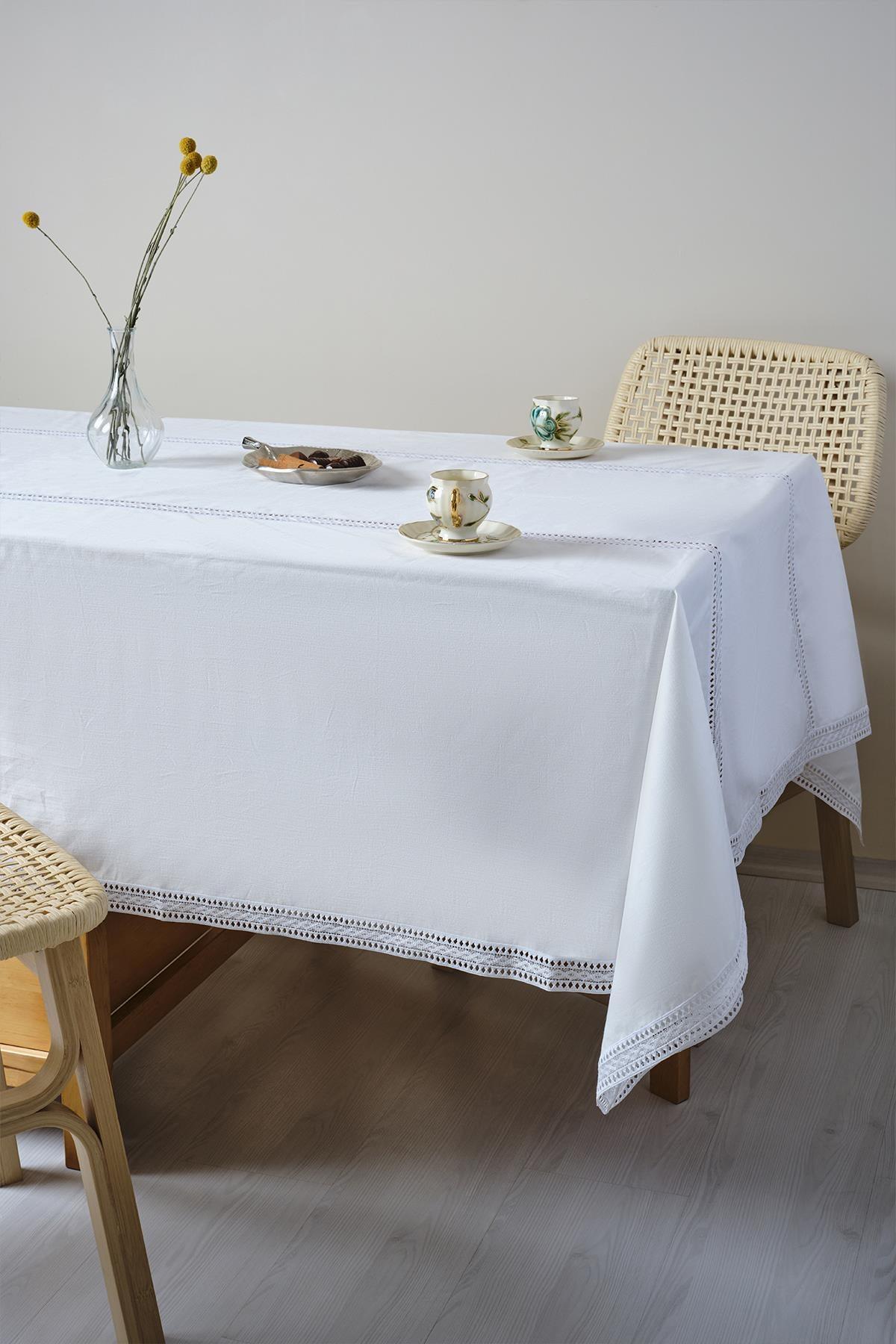 Mit einer weißen Tischdecke gedeckter Tisch mit Porzellantassen und einer Blumenvase