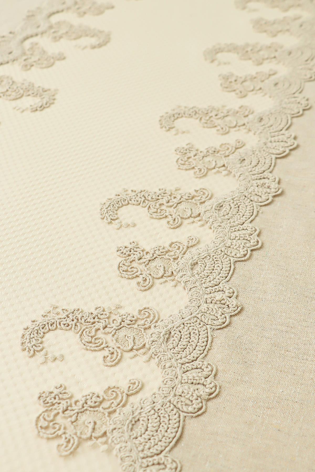 Cremefarbene Tischdecke mit Spitzendetails, elegantem Muster und strukturiertem Stoff.