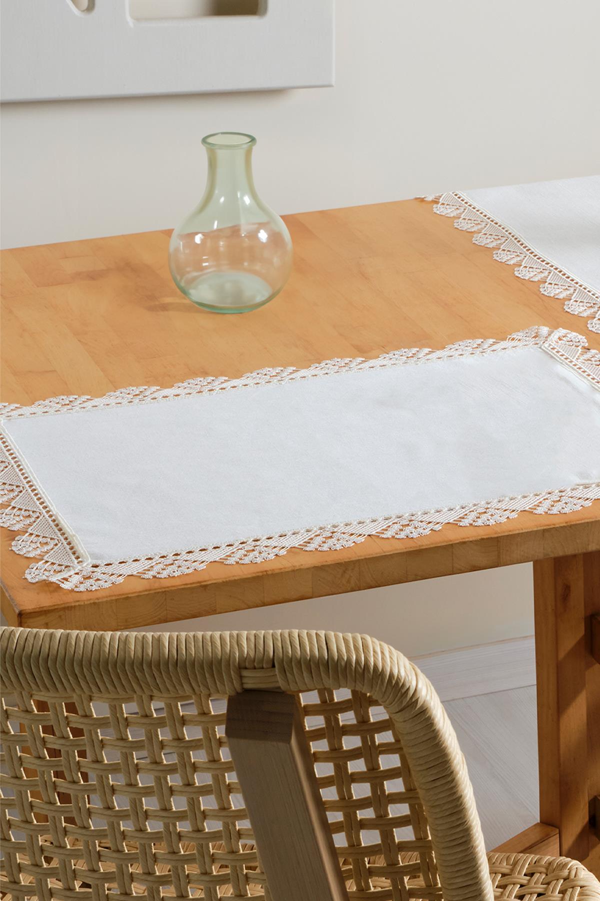 Weiße Platzdecke mit Spitzenrand auf einem Holztisch, Tischdekoration mit Glasvase